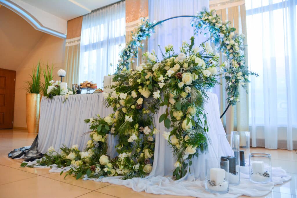Stół Młodej Pary pod kwiatowym łukiem w sali weselnej Ostoi